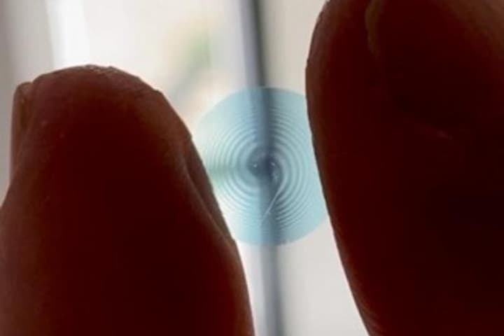 A sample spiral contact lens, held between the fingers of a researcher