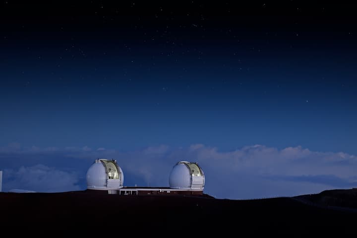 Two telescope domes on a hill at sunset
