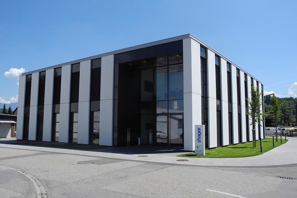 Modernes Hager-Bürogebäude mit Firmenschild und klarem Himmel