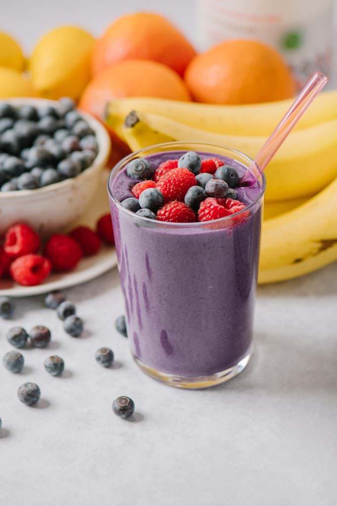 mixed berry smoothie in a glass with berries on top