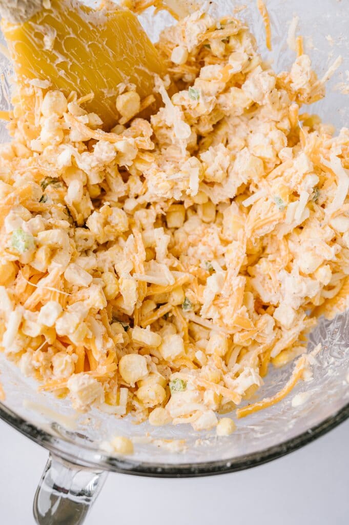 freshly mixed hot corn dip in a bowl with a spatula