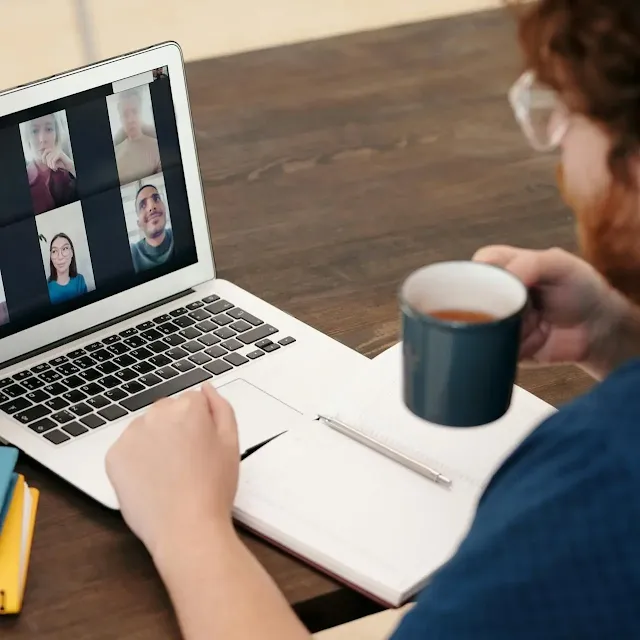 Man working at a laptop, with coffee cup in his hand.