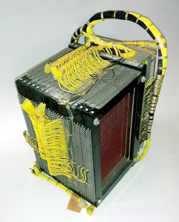 The 4000 character core memory module from an IBM 1401 computer. Tiny ferrite cores are strung on the red wires.