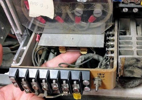 The 18V differential power supply in the IBM 1401 provides 12 volts to the core memory. The fuse is under the large electrolytic filter capacitors.