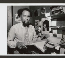 Black and white photograph of Howard Moore Jr. seated at desk.