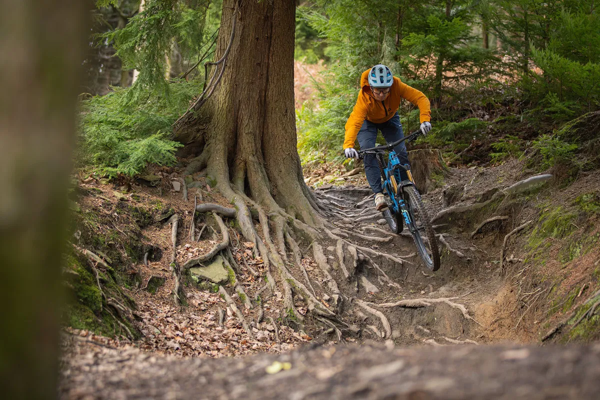 Male rider in orange riding the Pivot Switchblade Pro X0 Eagle Transmission full suspension mountain bike