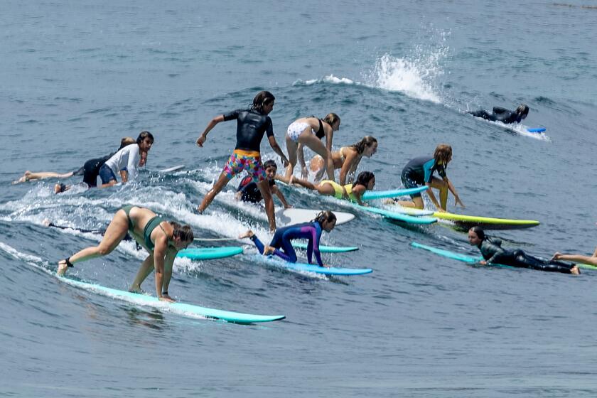 Laguna Beach, CA - August 10: A crowd of surfers attempt to ride a wave together as beach-goers frolic in the amid warm water on a hot and humid summer day in Laguna Beach Thursday, Aug. 10, 2023. (Allen J. Schaben / Los Angeles Times)