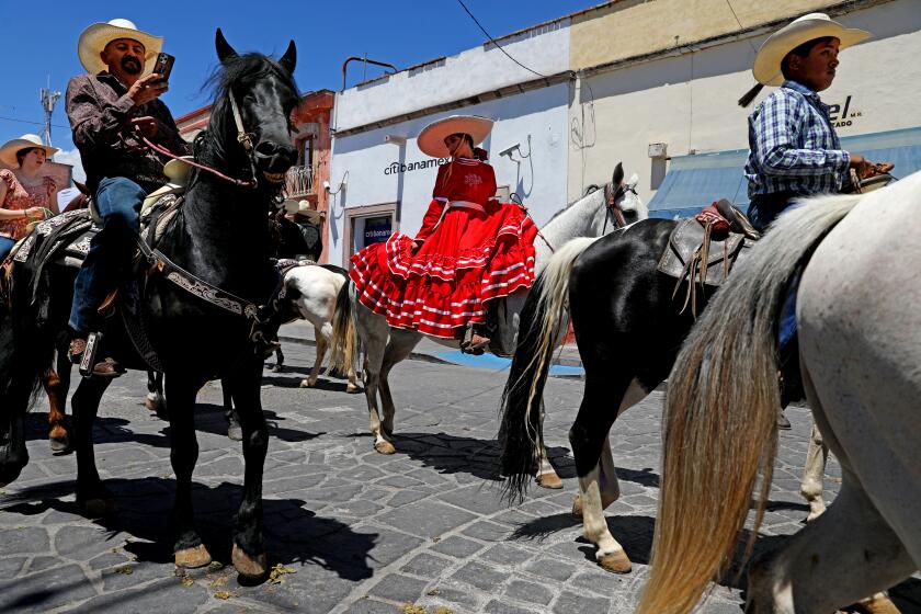 JEREZ, ZACATECAS - APRIL 08: Charros participate in a traditional cabalgata charra (parade of horses) wearing traditional charro garb on Sabado de Gloria (Glory Saturday or Holy Saturday) riding through the streets of downtown on Saturday, April 8, 2023 in Jerez, Zacatecas. Mexicans who immigrated to the United States, hoping to retire building houses in their hometowns in Mexico, are hesitant to return because of cartel violence. (Gary Coronado / Los Angeles Times)