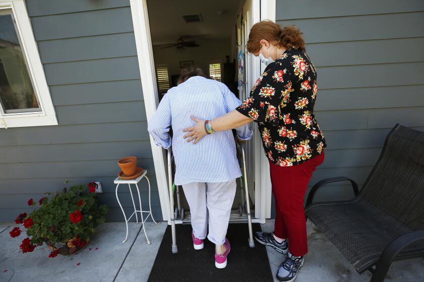 THOUSAND OAKS, CA - APRIL 15: Kim Ballon a Ventura County In Home Support Services (IHSS) care provider attends to Marjorie Williams, 84, at her Thousand Oaks home as California does little to track safety of health care workers during the coronavirus Covid-19 pandemic. Ballon is worried about a lack of protective gear though she regularly cares for elderly clients, helping them bathe and multiple tasks. (keep as a silhouette) Thousand Oaks on Wednesday, April 15, 2020 in Thousand Oaks, CA. (Al Seib / Los Angeles Times)