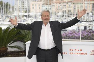 Alain Delon in a suit at without a tie posing at the Cannes Film Festival with his arms open wide