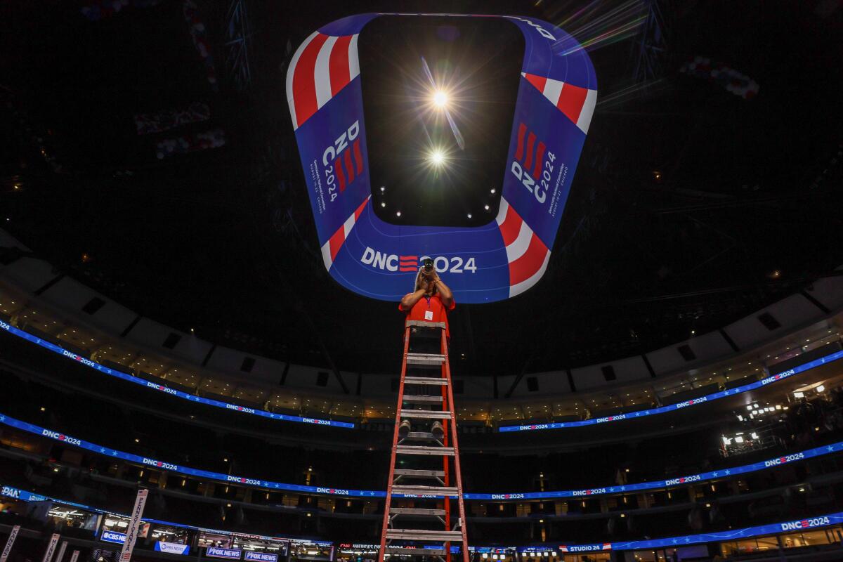 A woman climbs a tall ladder in a stadium