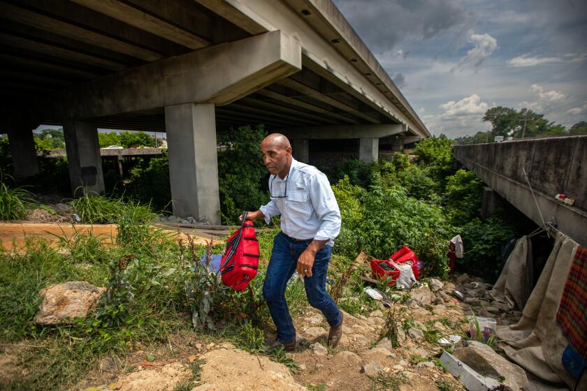 Jackson, MS - June 05: Tommie Brown, a homeless outreach coordinator with Stewpot Community Services walks up a rocky slope after bringing a homeless man bottles of cold water on June 5, 2023, in Jackson, MS. Mr. Brown is a retired police officer who is now helping the homeless community in Jackson, MS. (Francine Orr / Los Angeles Times)