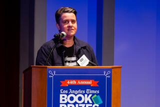 A woman in a black T-shirt and black jacket stands at a lectern with the Los Angeles Times Book Prizes logo.