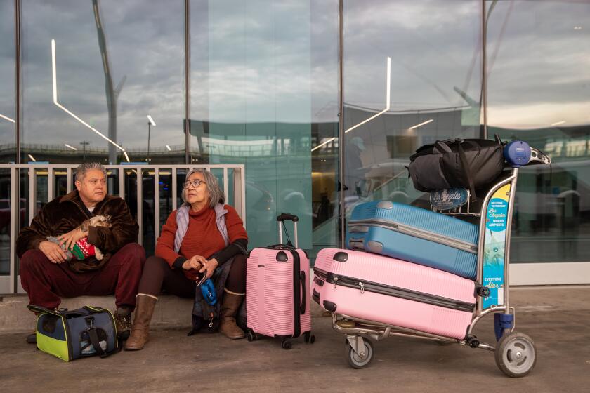 Los Angeles, CA - December 27: Luis Hernandez, 61, left, Ruth Hernandez, with their dog Sissi, from Torrance, wait for ride home after their Southwest Airlines flight to Omaha got cancelled at LAX Southwest Terminal 1 on Tuesday, Dec. 27, 2022 in Los Angeles, CA. (Irfan Khan / Los Angeles Times)