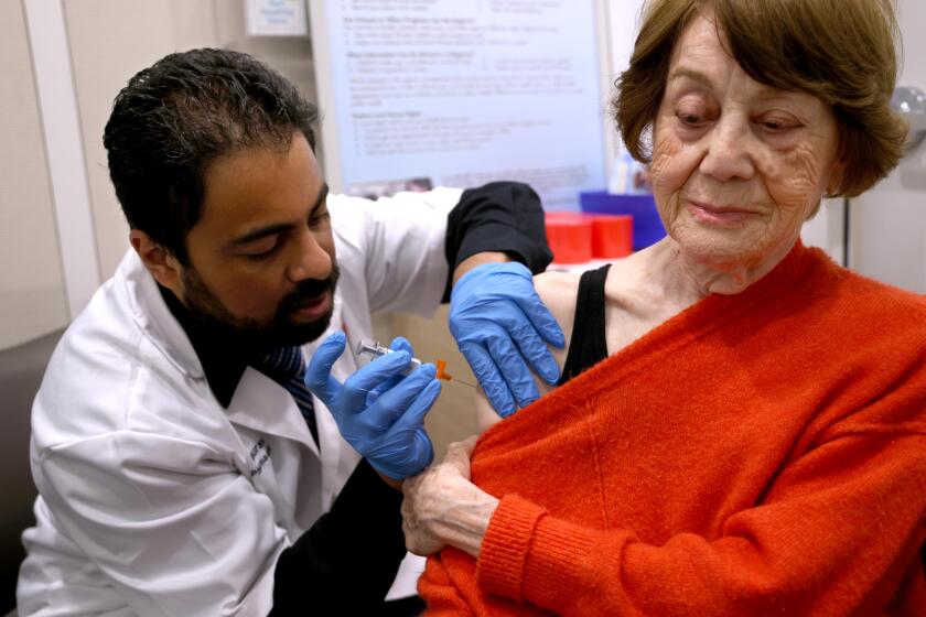 TORRANCE, CA - SEPTEMBER 5, 2024 - Dr. Gaurav Shinde gives Giti Noroozi, 85, her vaccinations for COVID and her flu shot at the Walgreens pharmacy in Torrance on September 5, 2024. In this photo Noroozi received the Fluzone H,D. for influenza. (Genaro Molina/Los Angeles Times)