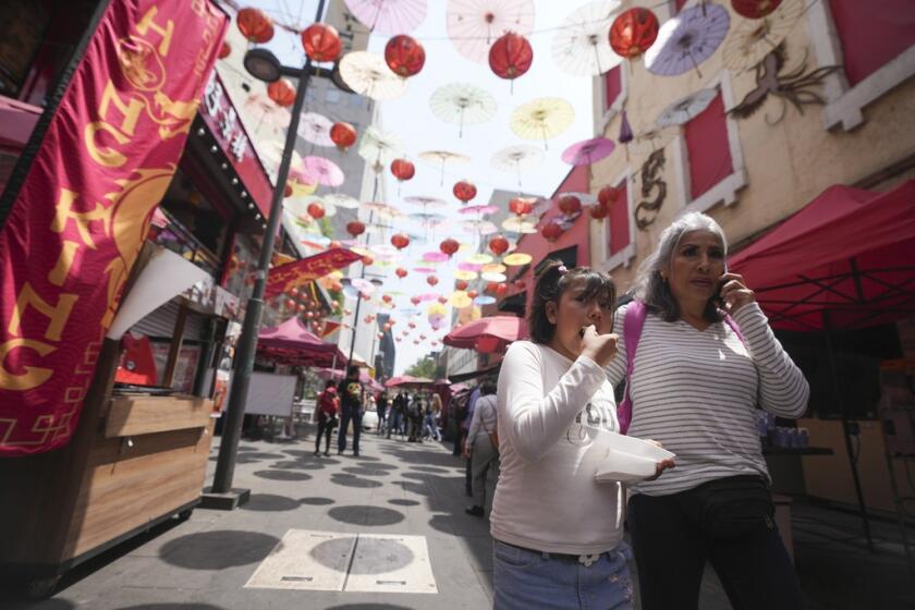 Turistas caminan bajo las sombrillas y lámparas 