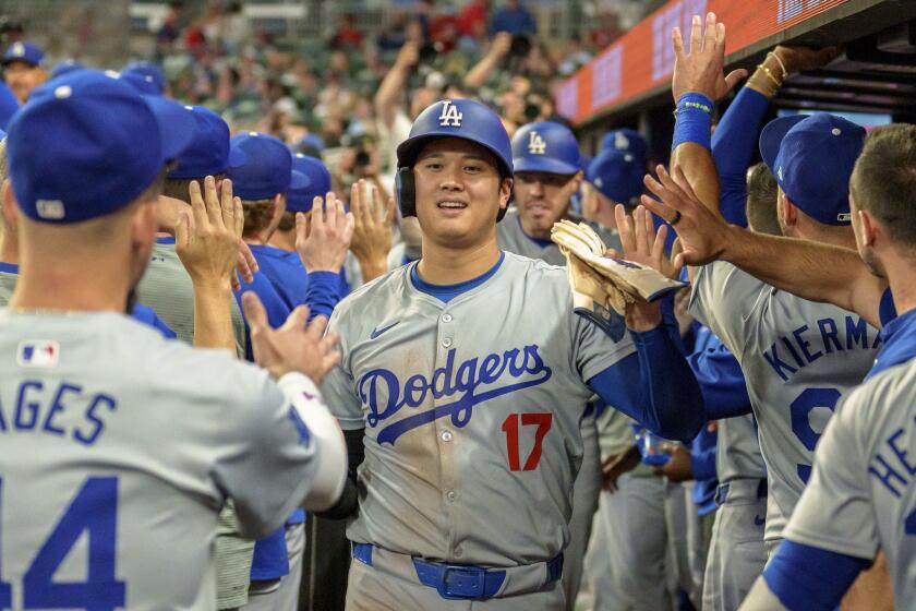 Shohei Ohtani de los Dodgers de Los Ángeles celebra en el dugout tras anotar con el jonrón de Freddie Freeman en la séptima entrada ante los Bravos de Atlanta el lunes 16 de septiembre del 2024. (AP Foto/Jason Allen)