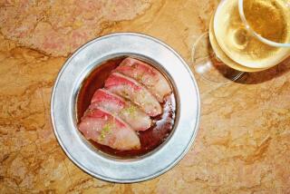 A dish of hamachi crudo ion a silver plate next to a glass of white wine at Barr Seco in Silver Lake.