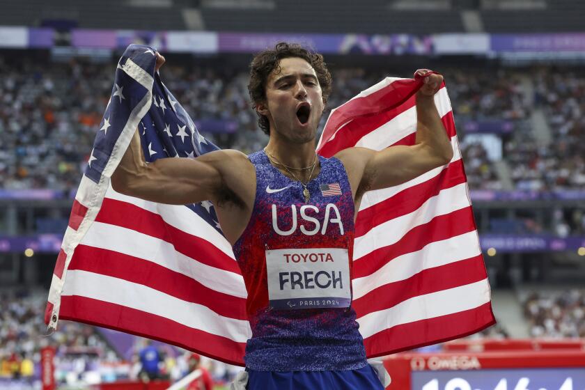 United States' Ezra Frech lifts the American flag after winning the T63 men's 100-meter final.