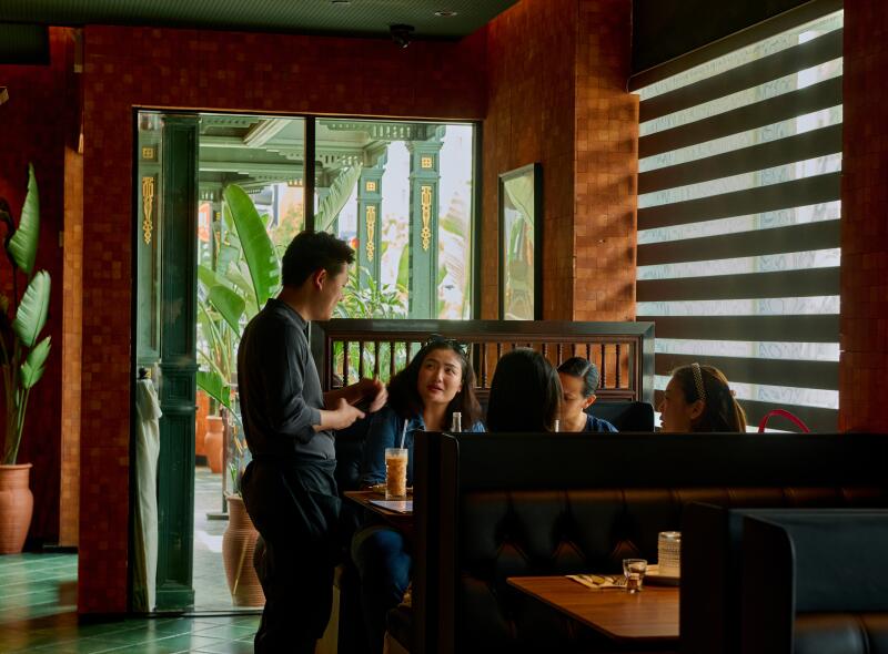 Guests ordering inside Star Leaf, surrounded by wood paneled walls, next to a slatted window.