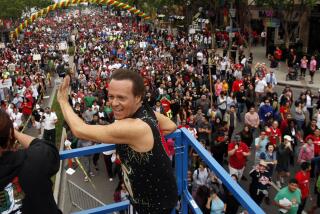 Richard Simmons waving to a group of people from a metal platform in West Hollywood