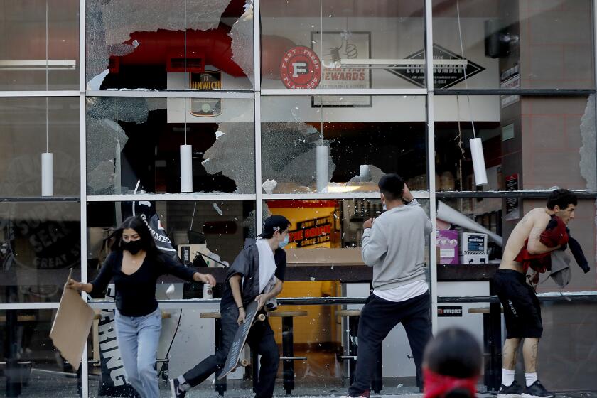 LOS ANGELES, CALIF. - MAY 30, 2020. Protesters break windows along Figueroa Street in downtown Los Angeles on Saturday, May 30, 2020. About 200 people marched through downtown streets, slowing traffic and keeping ahead of police trying to cut them off. Looting and the destruction of public and private property has spread across the country in the wake of the the police killing of George Floyd, a black man in Minneapolis. (Luis Sinco/Los Angeles Times)