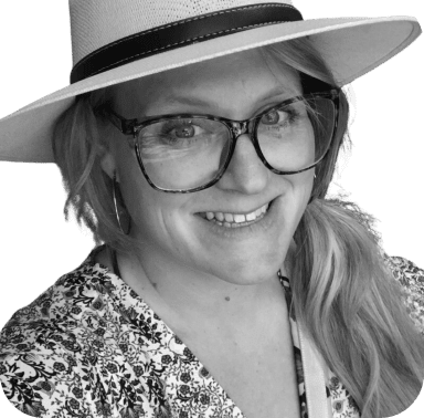 A black and white photo of a woman wearing glasses and a hat.