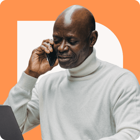 A man talking on a phone while using a laptop.