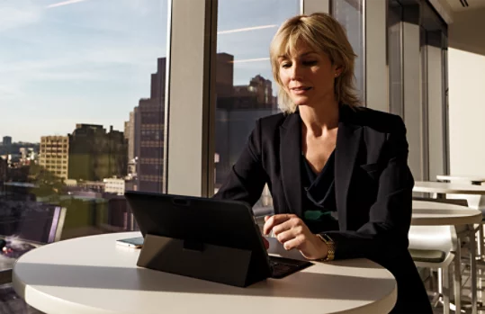 Business woman working on a two in one device in a high rise cafeteria.