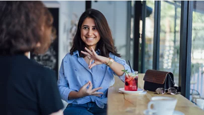 Two young woman speak in sign language.