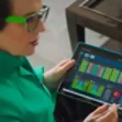 A person is holding a tablet displaying colorful charts and graphs.