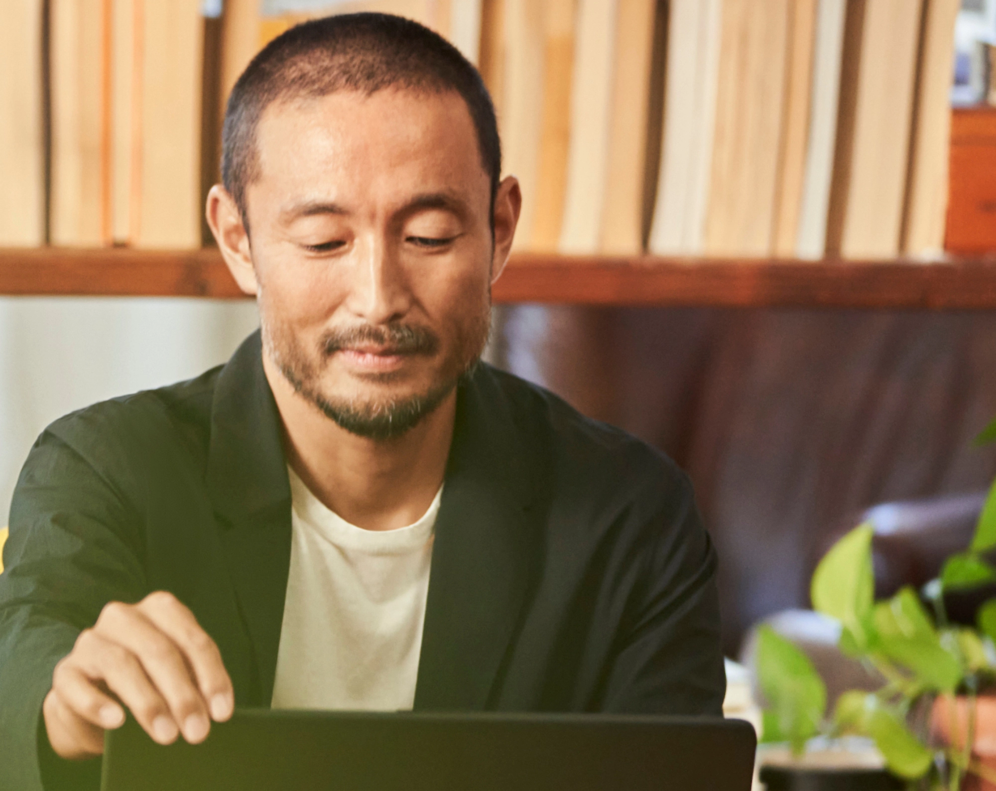 一位男士在家中办公室使用笔记本电脑