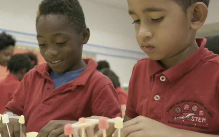 Young students in school uniforms play with educational toys in a classroom.