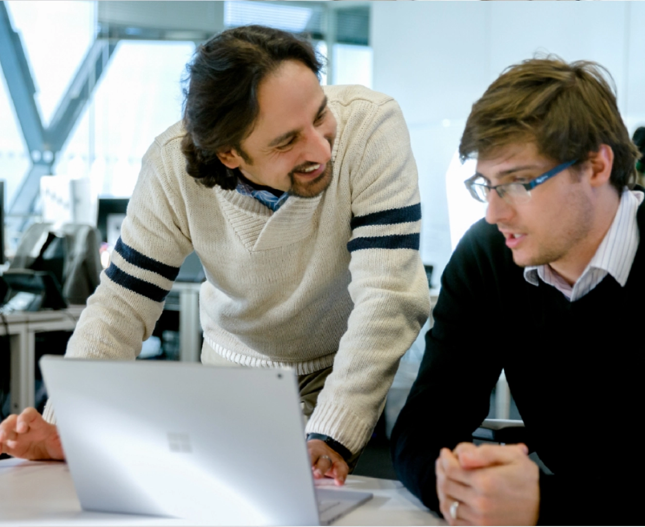 Dos personas en la oficina mirando un portátil y debatiendo