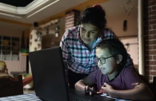 Mother and daughter working on a laptop in a rural home setting