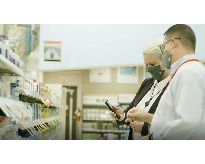 Dos personas con mascarillas en una farmacia.