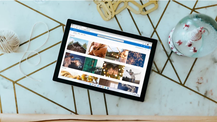 A Surface 2-in-1 PC with a OneDrive photo album on its screen