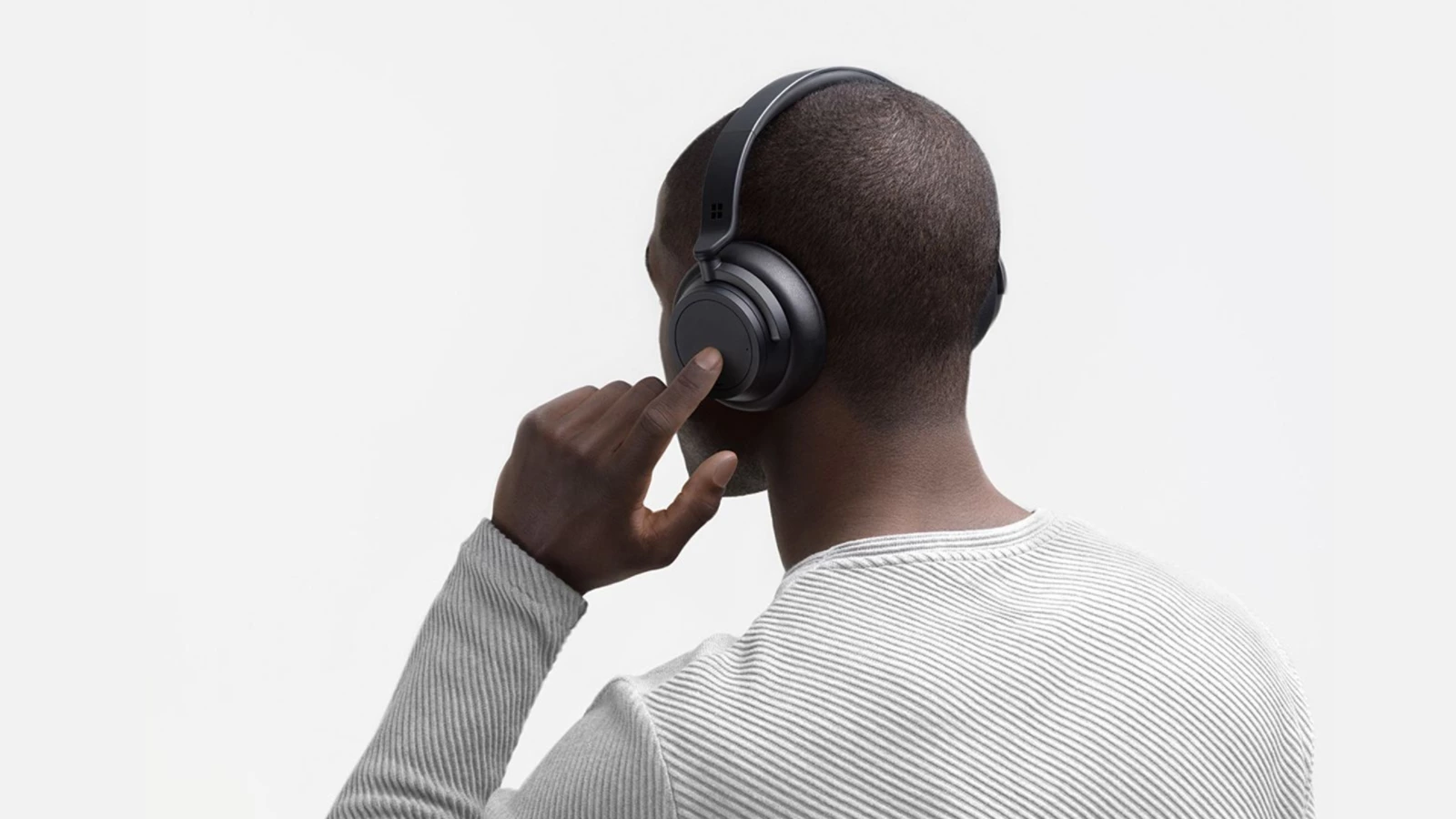 Henkilö päässään Surface Headphones 2+ käyttämässä kosketuspainikkeita