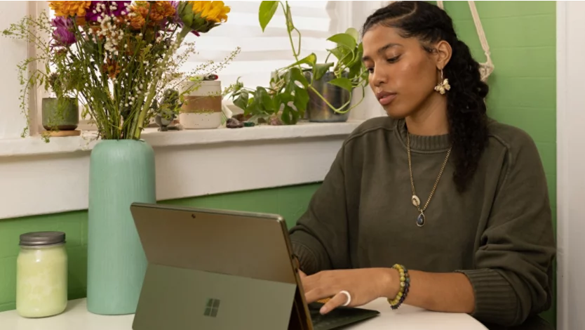 A woman sitting at a table using a laptop computer