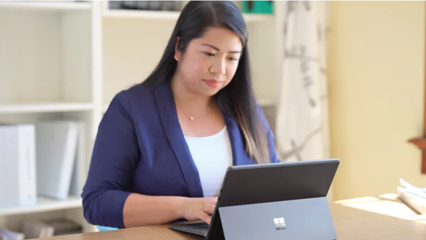 A woman working on a Microsoft Surface 2-in-1 PC