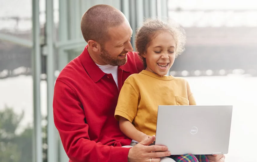 Mężczyzna i dziewczynka śmiejący się i patrzący na laptop