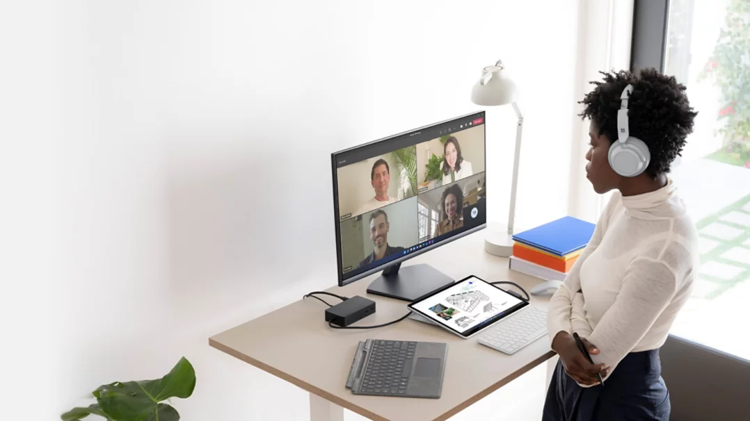 A person is observed standing at their home office desk while using Surface Pro 8 and multiple Surface accessories