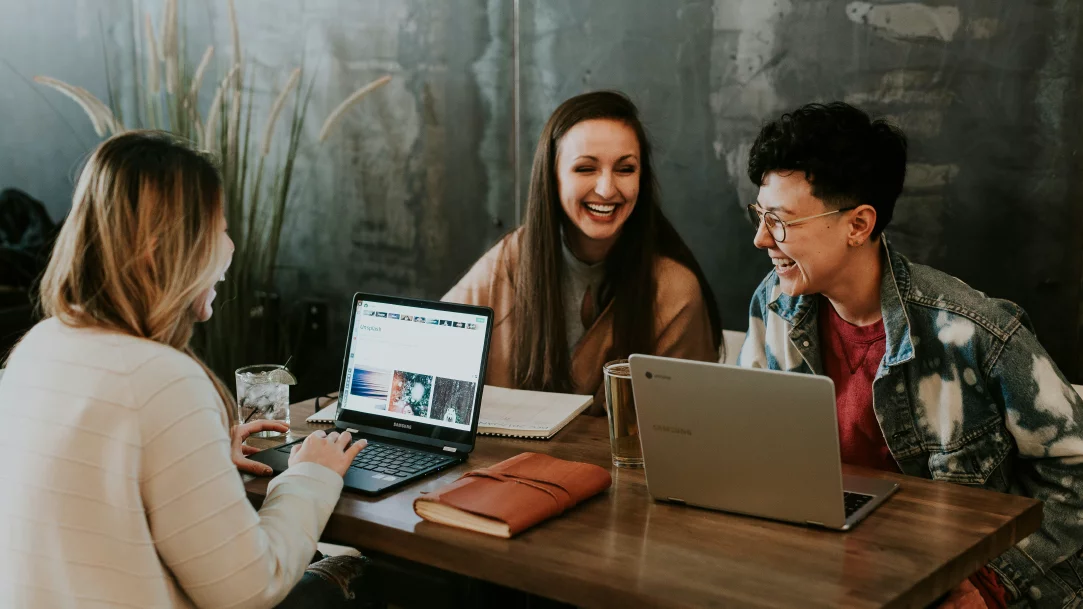 Three people studying at a table with their computers