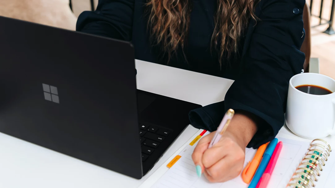 Woman taking notes next to Windows laptop