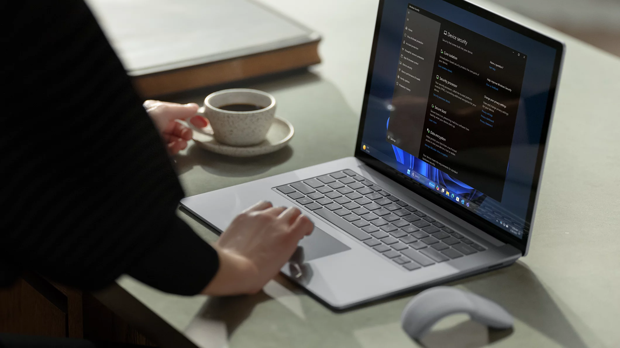 Femme travaillant à son bureau sur un ordinateur portable avec un café dans une main