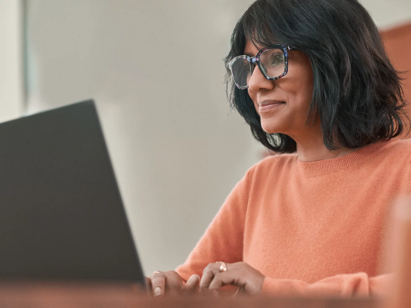 En kvinna med glasögon som arbetar vid en bärbar dator