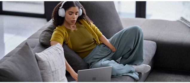 Una chica con auriculares trabaja en un portátil.