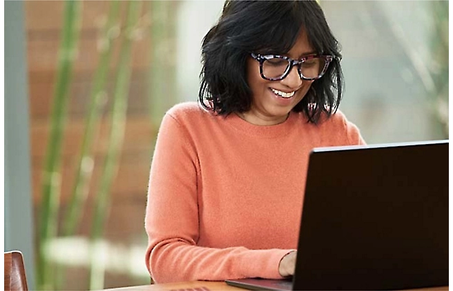 Una persona con gafas sonriendo frente a un equipo