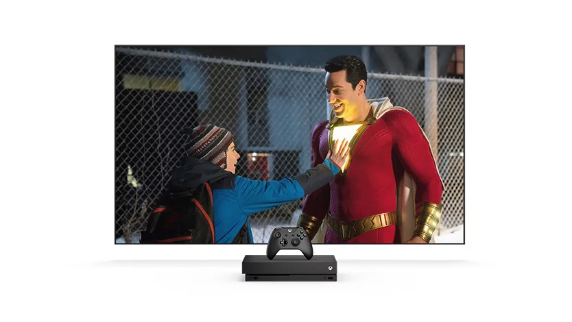  TV screen showing a boy touching a man chest that is lit up in a superhero costume.