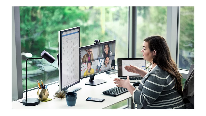 Female working at desk with multiple devices and running a Microsoft Teams conference call.